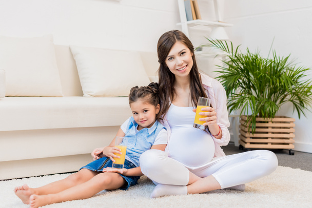 Pregnant woman and daughter with glasses of juice - Foto, imagen