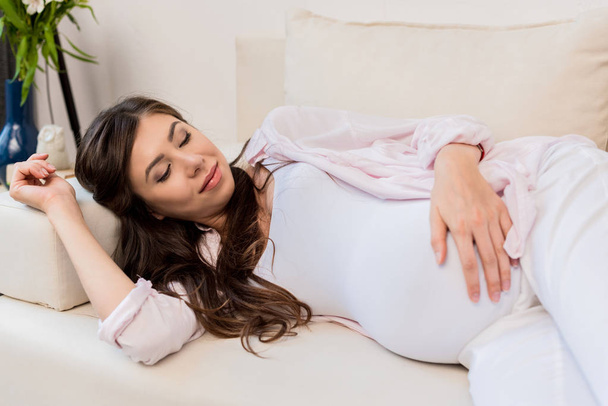 Donna incinta sdraiata sul divano
 - Foto, immagini