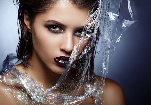 Beauty fashion model girl with bright make up. Fashion art portrait. With polyethylene film - Photo, Image