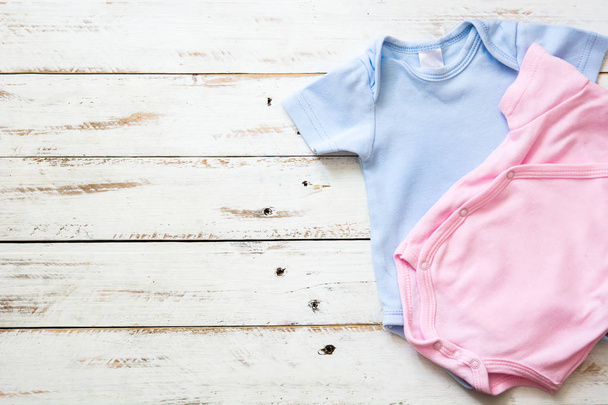 Pink and blue baby romper on white wooden background - Photo, Image