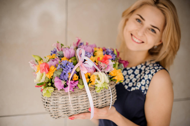Pretty blonde girl with basket of different flowers - Fotoğraf, Görsel