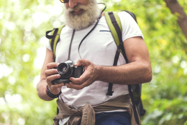 Cheerful mature tourist taking photos of forest - 写真・画像