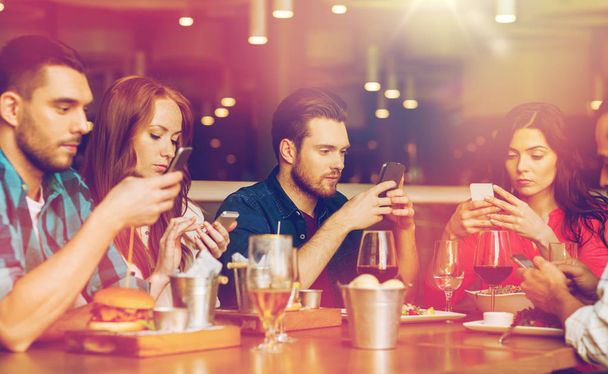 friends with smartphones dining at restaurant - Valokuva, kuva