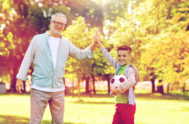 old man and boy with soccer ball making high five - Фото, зображення