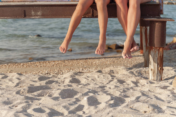 ビーチの砂の上にぶら下がっている足の 2 つのペア - 写真・画像
