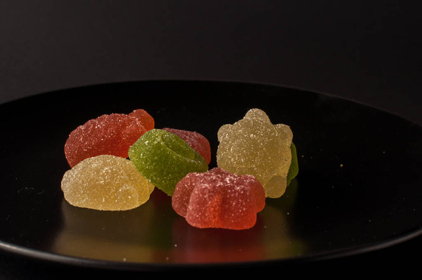 Gros plan de bonbons colorés. gelées aromatisées aux fruits mélangés sur une assiette noire
 - Photo, image
