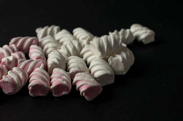 Marshmallows su sfondo nero con copyspace. Lato piatto o vista dall'alto. Sfondo o texture di mini marshmallow colorati
. - Foto, immagini