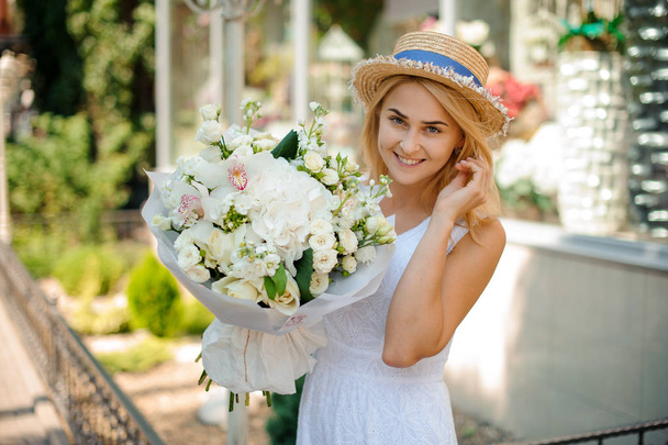 White wedding bouquet in hands of a cute girl in a hat - Foto, imagen