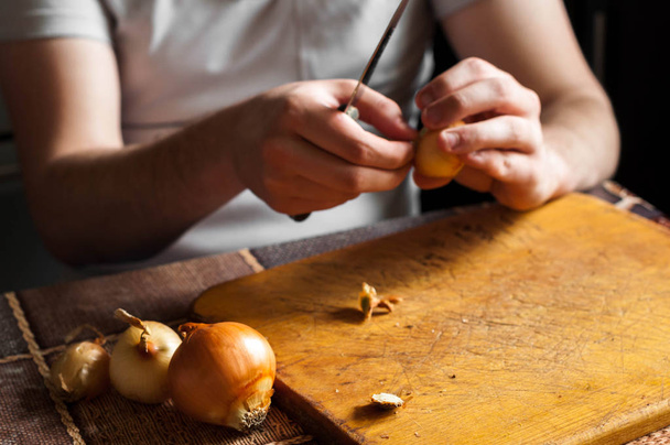 Ο άνθρωπος που καθαρίζει ένα μαχαίρι και κόβουμε το κρεμμύδι - Φωτογραφία, εικόνα