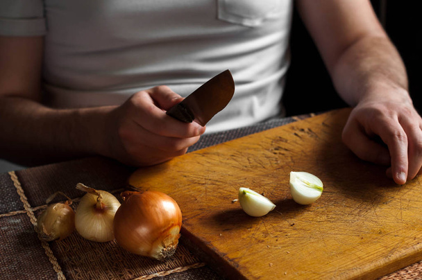 Couper et hacher un oignon sur une planche de bois avec un couteau
 - Photo, image