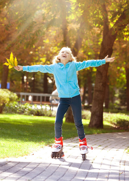 Little Girl Riding on Rollers and Enjoying Sunny Autumn Day - Photo, image