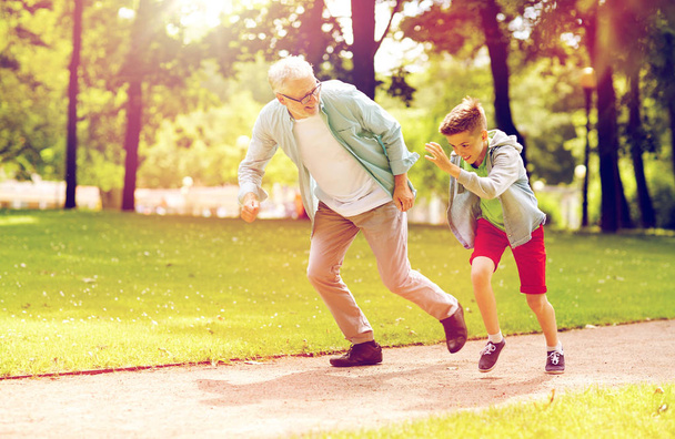 grandfather and grandson racing at summer park - Фото, изображение