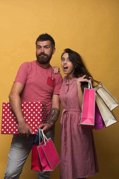 Couple holding shopping bags on yellow background - Foto, Imagem
