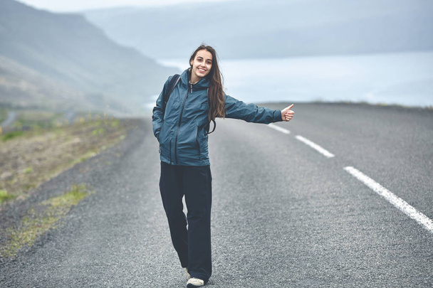 una turista en el camino vacío en el fiordo en Islandia
 - Foto, imagen