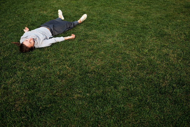 Beautiful young european woman lays down on grass and rests - Photo, image