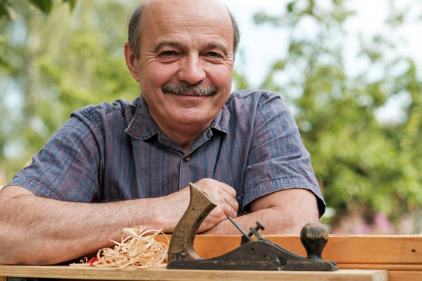 Mann händigt Zimmermannshobel auf Holzgrund aus - Foto, Bild