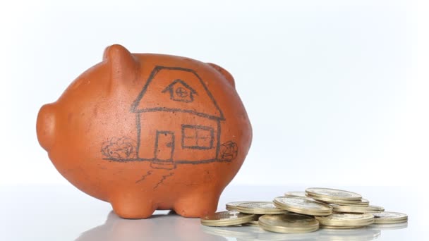 Woman saving money into a traditional clay piggy bank for a house - Footage, Video