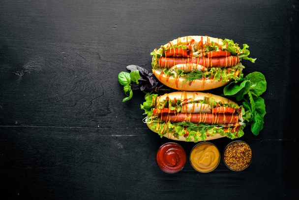 Hot dog with grilled sausage, mustard and ketchup, onions and greens on Wooden background. Top view. Free space. - Photo, image