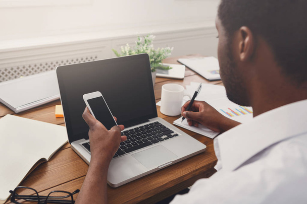 Афро-американський бізнесмен в офісі з мобільний та ноутбук - Фото, зображення