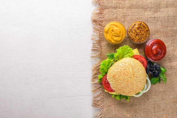 Hamburger with cheese, meat and green onions on Wooden background. Top view. Free space. - Foto, afbeelding