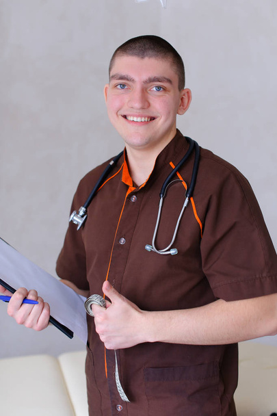 Профессиональный мужчина-терапевт смотрит в камеру с улыбкой и стоит
 - Фото, изображение