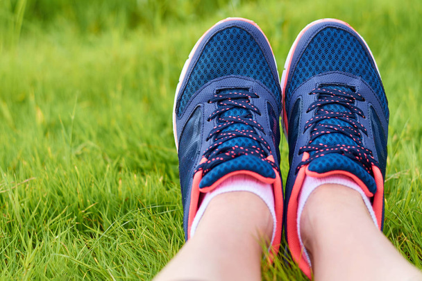 A lábak, a lány a cipők feküdni a zöld fűben. Pihenés, sportolás után. Fogalmának egy egészséges életmód és a sport - Fotó, kép