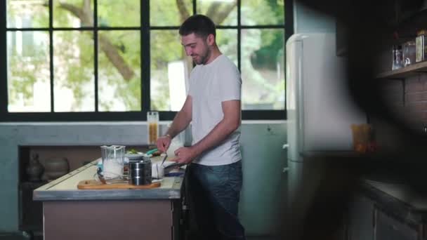 The man is cooking a dinner and smiling - Imágenes, Vídeo