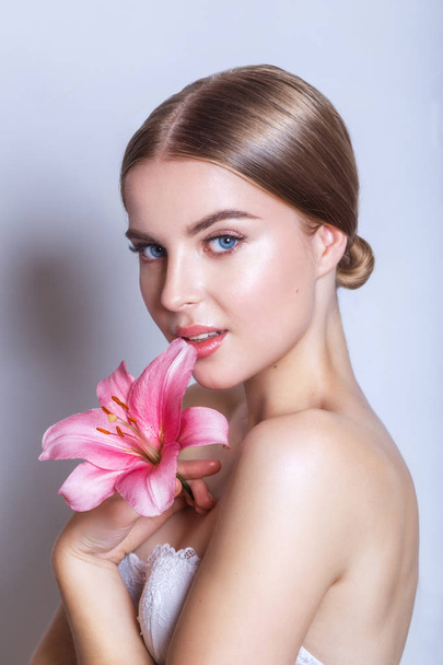 Beauty face of young woman with flower. Beauty treatment concept. Portrait over white background - Fotó, kép