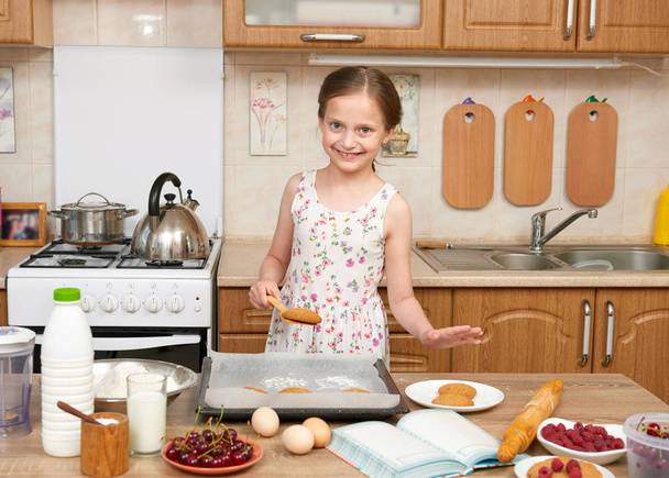 Девочка печет печенье на домашней кухне. Сырая еда и фрукты. Концепция здорового питания
. - Фото, изображение