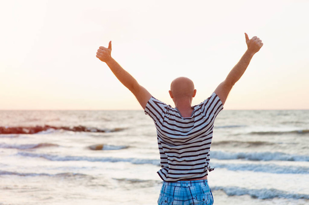 Ευτυχισμένος άνθρωπος θέτει τα χέρια του επάνω ενάντια στη θάλασσα - Φωτογραφία, εικόνα