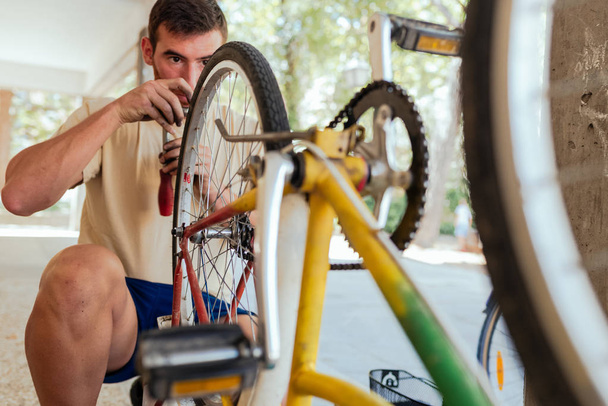 Mies tarkistaa hänen pyörä Wheel jälkeen korjataan
 - Valokuva, kuva