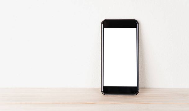 El teléfono de pantalla blanca descansa contra la pared
 - Foto, imagen