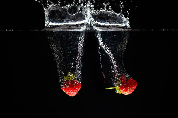 zwei Erdbeeren, die ins Wasser spritzen - Foto, Bild