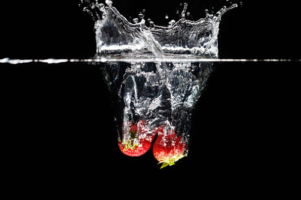 Two strawberrys splashing into water - Фото, зображення