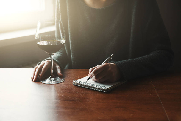 female hands with pen and glass of wine - Photo, Image