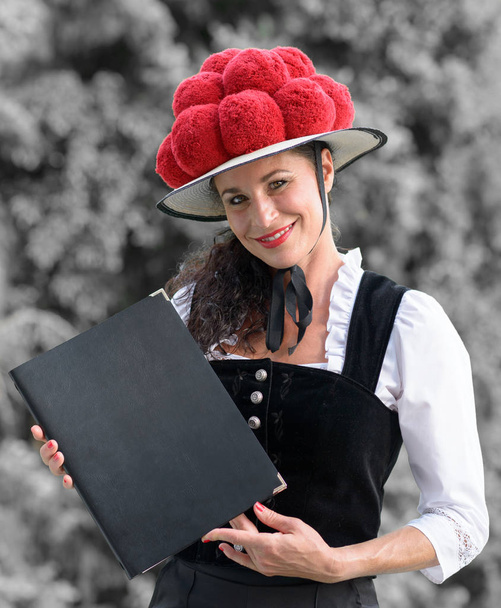 Γερμανικά σερβιτόρα κρατώντας ένα μενού φορώντας ένα bollenhut - Φωτογραφία, εικόνα