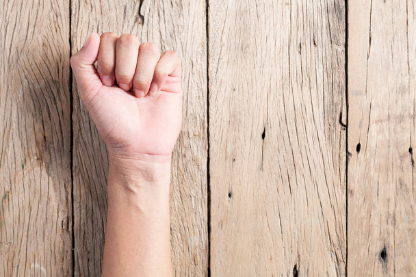 Male clenched fist on wood background. - Photo, Image