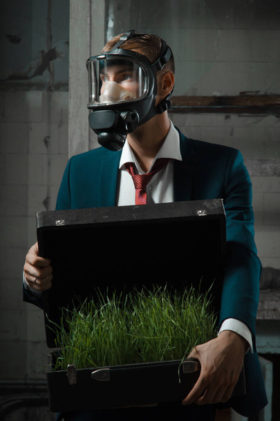 the photo of man in gas mask with suitcase. in the suitcase sprouted wheat - Photo, Image