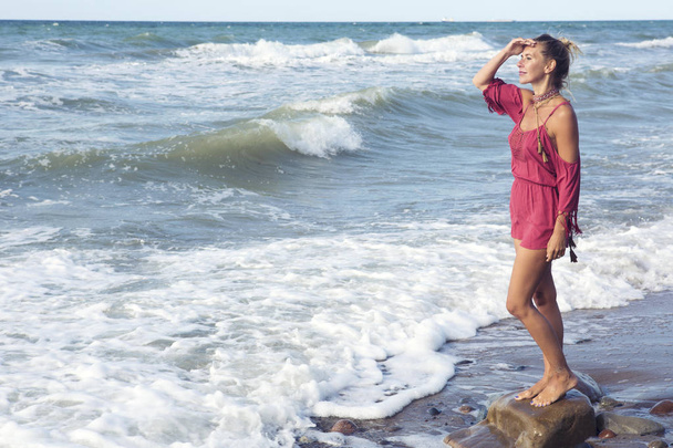 blond woman in red dress standing by the ocean - Фото, зображення