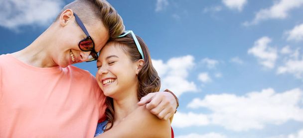 happy teenage couple hugging over blue sky - Φωτογραφία, εικόνα