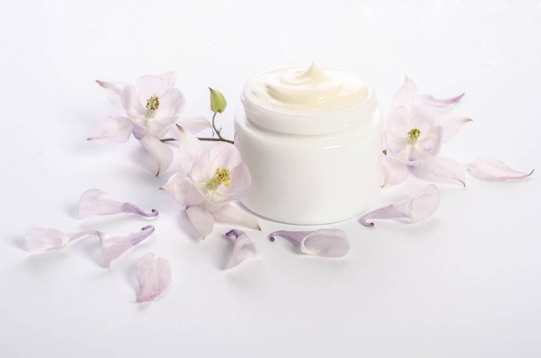 Cute flowers and petals and a jar of natural body cream - 写真・画像