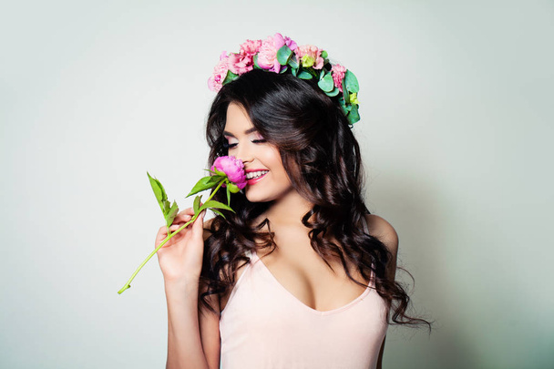 glückliche brünette Frau mit langen lockigen Haaren und Frühlingsblumen - Foto, Bild