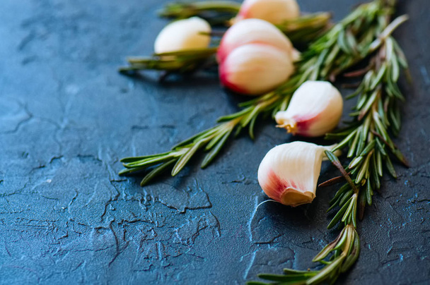 Garlic cloves and rozmary on a black background - Photo, image