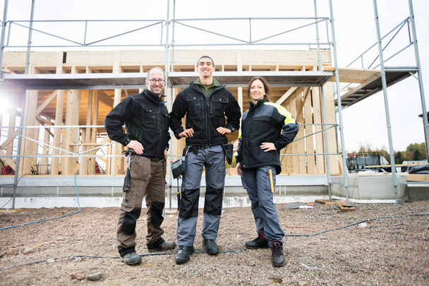Carpenters Standing With Hands On Hips At Construction Site - Foto, afbeelding