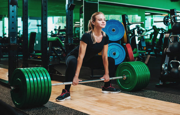 Kadın gerçekleştirme deadlift egzersiz ile kilo bar yapmak - Fotoğraf, Görsel
