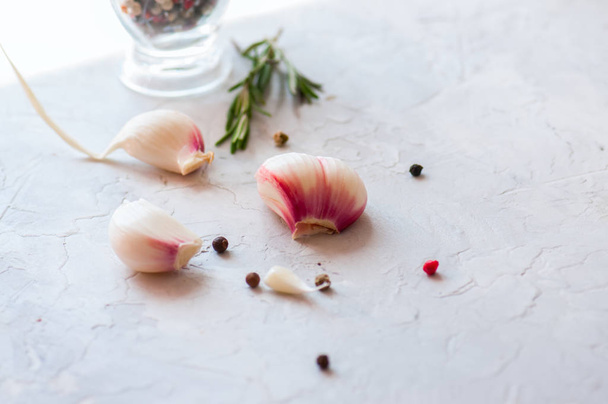 Garlic cloves, pepper corns and rosemary on a white background - Photo, image