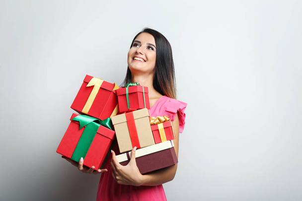 Portrait of beautiful woman holding gift boxes on grey backgroun - Foto, afbeelding