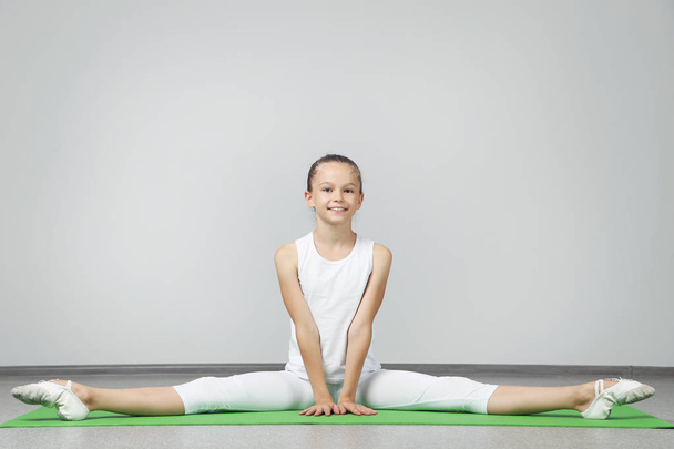 Young girl doing exercises on green yoga mat - Foto, Imagem