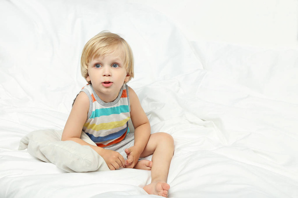 Little boy sitting in white bed - Фото, изображение