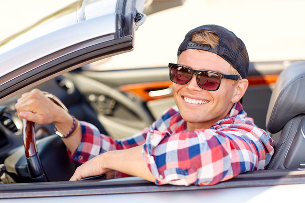 happy young man in shades driving convertible car - Photo, image